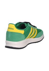 Sneaker Adidas verde e giallo con lacci neri, strisce gialle sui lati e suola bianca, vista dal retro destro.