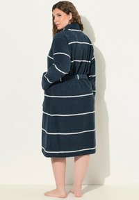 Vesimustasi kylpytakki, jossa on valkoisia vaakasuoria raitoja, pitkät hihat, vyö ja sivutasku. Sileä rakenne, polven pituinen.