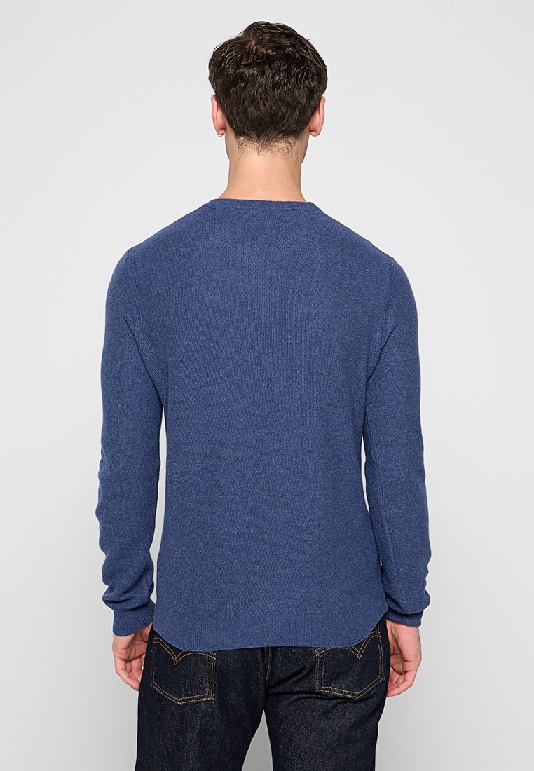 Maglione azzurro a maglia con scollatura a girocollo, maniche lunghe e un aspetto texturizzato, con un orlo leggermente curvato e polsini a costine.