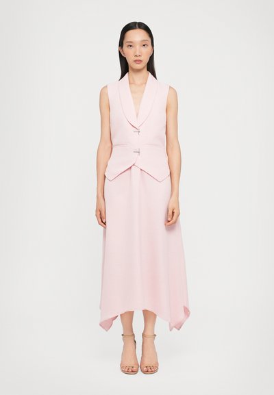 Rosa ärmelloses Oberteil mit V-Ausschnitt und doppelten Knöpfen, kombiniert mit einem langen Rock mit asymmetrischem Saum und weicher Textur.