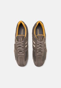 Baskets en daim brun et mesh avec des accents jaunes, présentant des rayures blanches, un bout rond et un design à lacets. Marquage Geox sur la semelle intérieure.