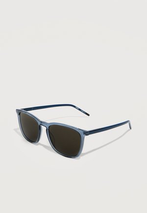 Rektangulære solbriller med blå ramme og mørke linser, der hviler på en hvid overflade, med mærkenavnet "Hugo" på stangen.