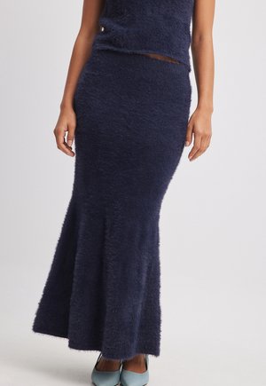 Marineblau, flauschiger Strickrock mit enganliegendem Bund und ausgestelltem Saum. Weiche Textur und glatte Verarbeitung, kombiniert mit hellblauen Schuhen.