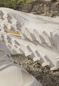Beżowe buty terenowe z teksturowanymi powierzchniami, solidną podeszwą z wyraźnymi wypustkami oraz wyraźnym oznaczeniem "Continental".