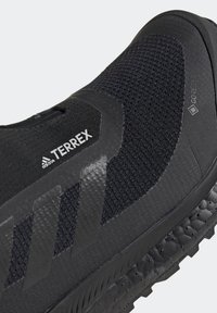 Chaussure de trail running Adidas Terrex noire avec tige en mesh respirant et semelle texturée équipée de la technologie imperméable Gore-Tex.