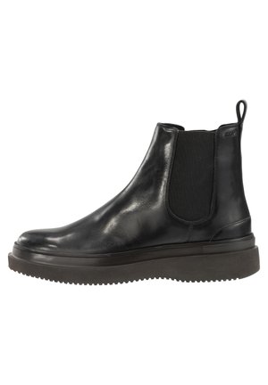 Botte Chelsea en cuir noir avec panneaux latéraux élastiques, semelle en caoutchouc épaisse et languette à l'arrière.