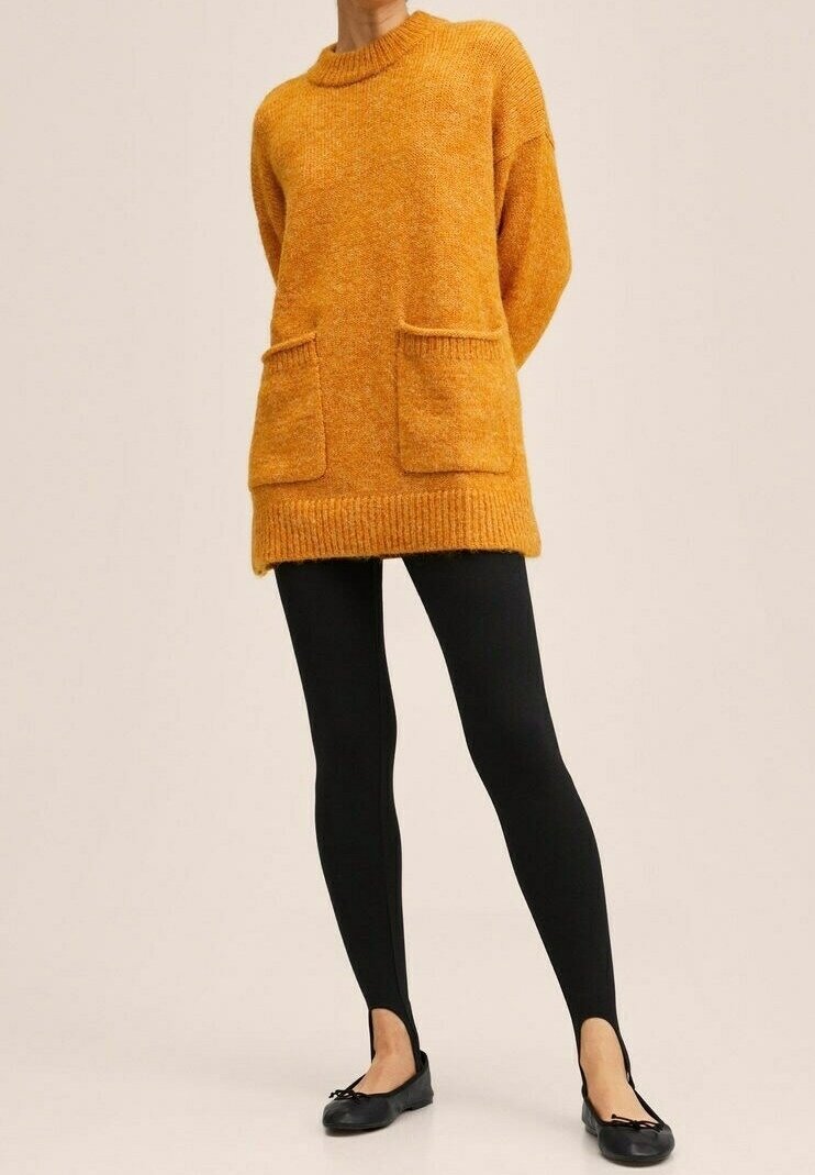 Pull en maille orange surdimensionné avec ourlet à cotes, deux poches avant et col rond, associé à des leggings noirs et des ballerines noires.
