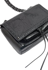 Czarna skórzana torebka crossbody o fakturowanej powierzchni, z klapą, metalowym łańcuszkiem oraz skórzanym chwostem jako detal wykończenia z przesuwnym sznureczkiem.