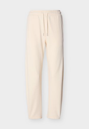 Φόρμες σε κρεμ χρώμα από μαλακό ύφασμα, με ελαστική ζώνη μέσης και κορδόνια, καθώς και στενά μπατζάκια. Χωρίς εμφανή σχέδια ή διακοσμητικά στοιχεία.