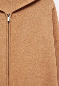 Sudadera con capucha y cremallera en tono bronce, confeccionada en una tela suave con un acabado texturizado, que presenta un cuello alto y un detalle de cremallera plateada en la parte frontal.