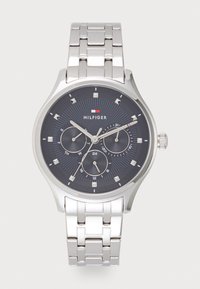 Montre en acier inoxydable argenté avec un cadran analogique bleu foncé, trois sous-dials et des accents argentés. Elle dispose d'un bracelet à maillons et d'indicateurs horaires marqués.