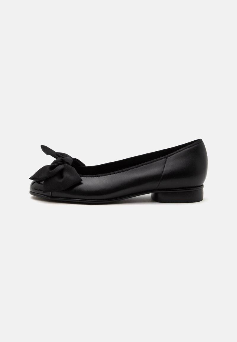 Chaussure plate en cuir noir avec un bout arrondi et un grand nœud en tissu sur le dessus, avec un petit talon et une finition lisse.
