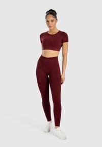 Bordeaux crop-top og matchende højtaljede leggings i et glat, strækbart stof; har korte ærmer og et tætsiddende design.