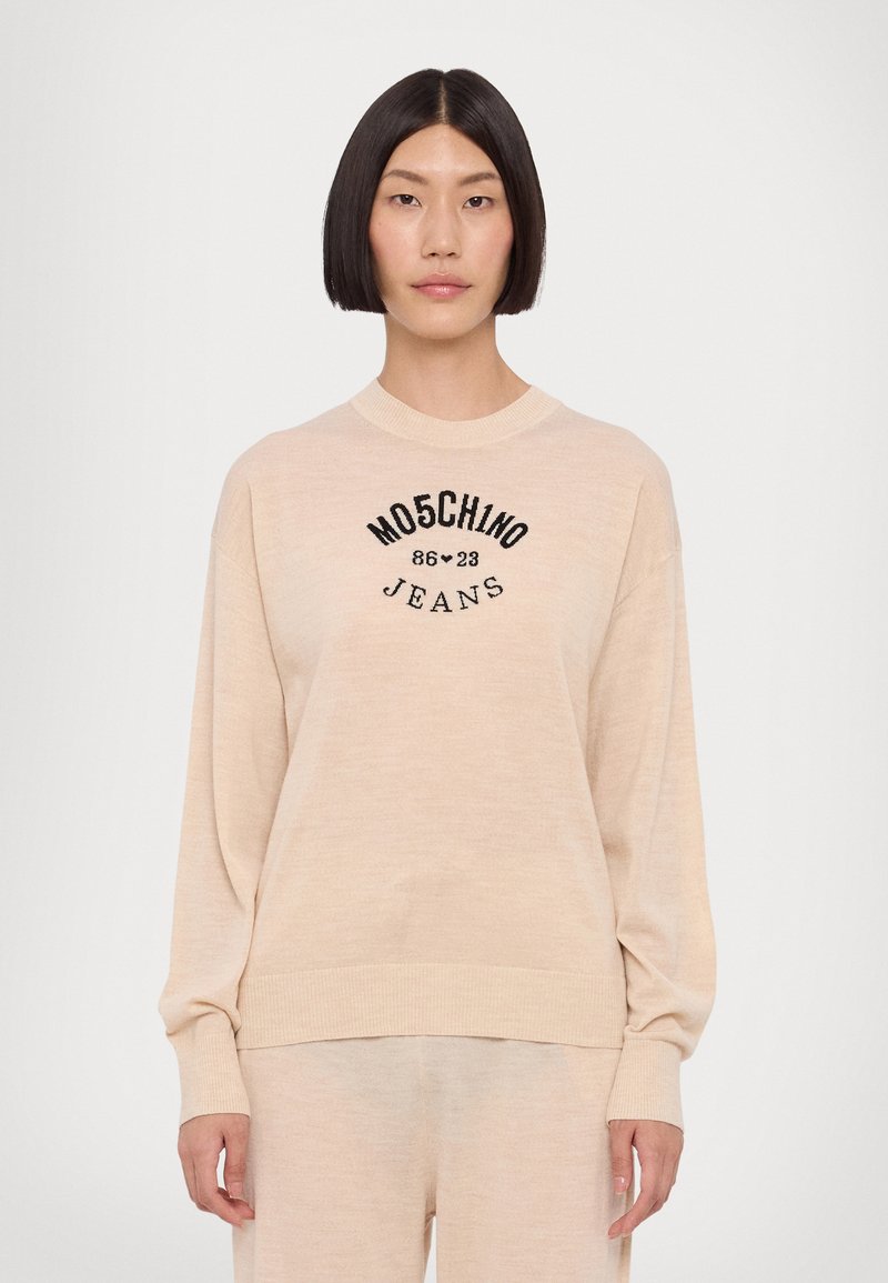 Sweater bege com decote redondo canelado e mangas compridas. Apresenta o logótipo preto "MOSCHINO JEANS 86-23" na frente. Textura suave.