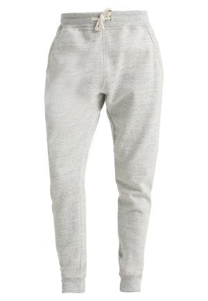Pantalon de survêtement gris clair en tissu doux et texturé. Dispose d'une taille élastique avec cordon de serrage et de poignets côtelés. Deux poches latérales.