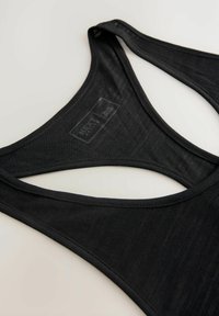 Crna majica na bretele s zaobljenim izrezom, dizenom s racerback, teksturiranom tkaninom i suptilnom oznakom brenda blizu ovratnika.