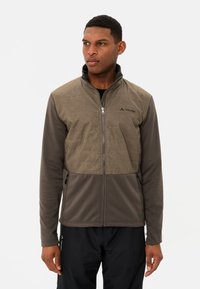 Veste cintrée zippée en tissu brun bicolore ; le haut présente un panneau texturé de couleur brun clair avec des poches latérales et des détails de logo noirs.