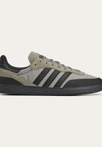 Gray and black sneakers featuring a suede and fabric combination, three black stripes, textured rubber sole, and lace-up design.