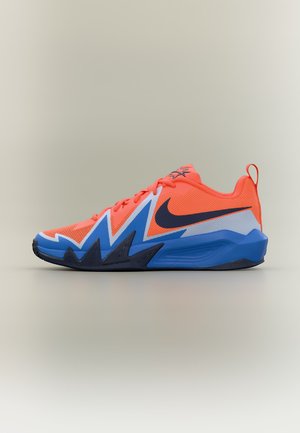 Svetlo narančasta i plava Nike tenisica sa cik-cak dizajnom, crnim Swoosh logotipom i jastučićem na potplatu, prikazana iz profila na neutralnoj pozadini.