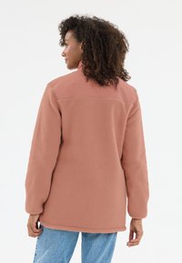 Fleece-Jacke in staubigem Rose mit glattem, einfarbigem oberen Bereich. Verfügt über lange Ärmel und eine lockere Passform, mit abgerundetem Saum und seitlichen Schlitzen.