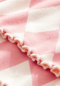 Roze-wit geruit stof met een getextureerd oppervlak; voorzien van gerimpelde randen en afwisselende vierkante patronen. Zacht en lichtgewicht materiaal.