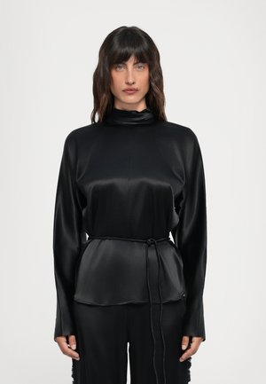 Zwarte satijnen top met lange mouwen en een hoge halslijn, met een koord in de taille voor een verstelbare pasvorm en een gladde, glanzende textuur.
