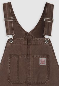 Koffiekleurige denim overalls met verstelbare schouderbanden, een borstzak aan de voorkant en een klein geborduurd Levi Strauss & Co. label op de zak.