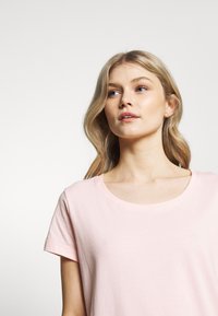 Lichtroze T-shirt met een ronde hals, korte mouwen en een zachte katoenen textuur, voorzien van subtiele stiksels.