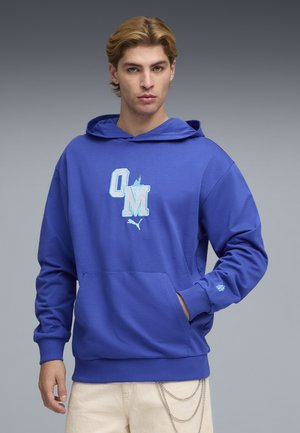 Blauer Hoodie mit Fronttasche und gesticktem "OM"-Logo. Verfügt über gerippte Bündchen und Saum, gefertigt aus weichem, strukturiertem Stoff.