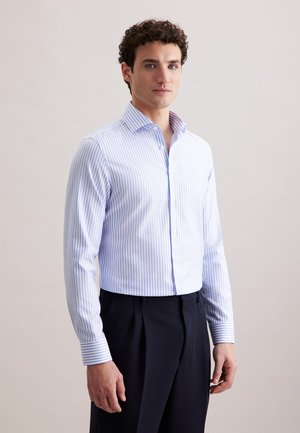 Chemise rayée bleu clair et blanche avec un col classique, des manches longues et une fermeture à boutons. Le tissu semble lisse et légèrement texturé.