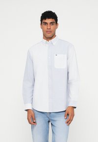 Πουκάμισο με κουμπιά, με αριστερή συμπαγή ανοιχτό μπλε πάνελ και δεξί πάνελ με λευκές ρίγες. Διαθέτει τσέπη και κανονικό для.