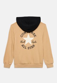 Μπεζ φούτερ με μαύρη κουκούλα. Φέρει ένα λευκό αστέρι και κείμενο "CONVERSE CHUCK TAYLOR ALL STAR" σε μαύρο στο πίσω μέρος. Μαλακή υφή.