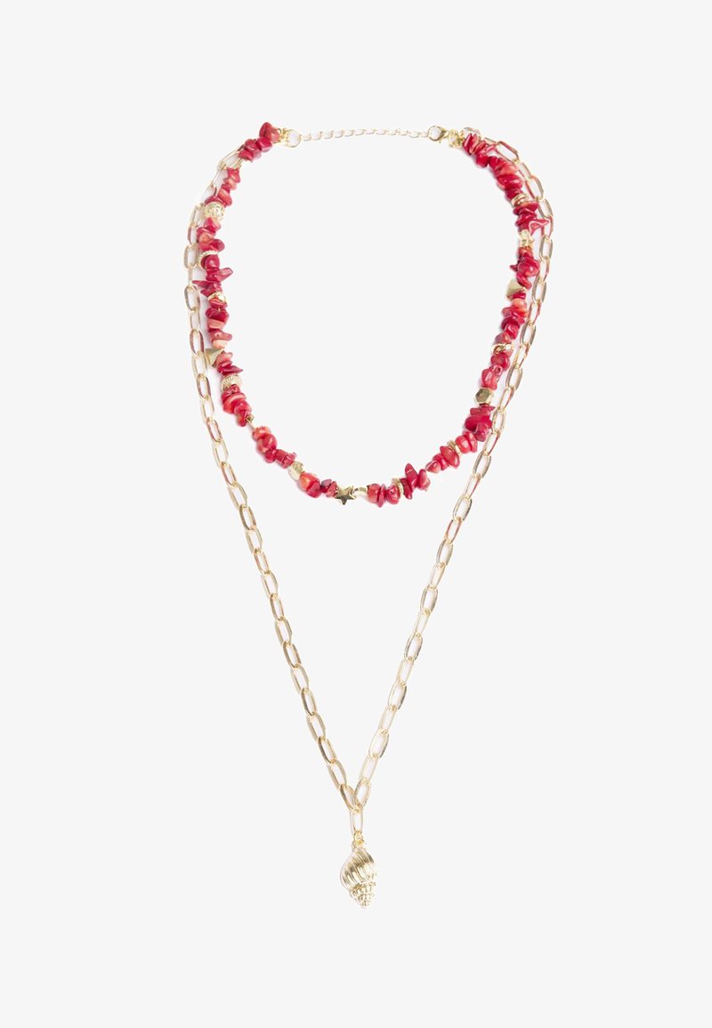 Collana in oro a due fili, uno con perline di pietra rossa e accenti, e un pendente a forma di conchiglia in oro al centro.