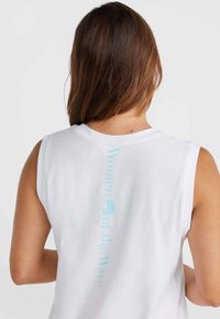 Vit ärmlös T-shirt med ljusblå texten "Women of the Wave" tryckt vertikalt på baksidan. Mjuk tygkvalitet, avslappnad passform och enkel design.