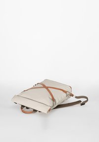 Zaino beige con design a strisce marroni a forma di X, realizzato in materiale morbido, dotato di spallacci imbottiti e superficie piatta e liscia.