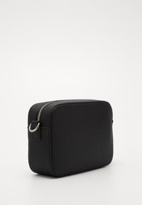 Černá obdélníková taška vyrobená z texturovaného materiálu se stříbrným zipem, bočním poutkem pro připevnění a minimalistickým designem.