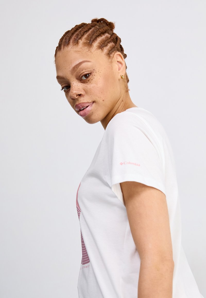 Weißes T-Shirt mit einem pinken Grafikdesign, das Linien und Text zeigt. Kurze Ärmel, weiches Baumwollmaterial, Columbia-Logo auf dem Ärmel.