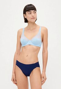 Sujetador azul claro con rayas texturizadas, superposición de malla y banda ancha; combinado con braguitas de bikini azul marino, ambos con tejido suave.