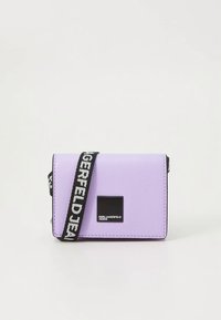 Violeta sintētiska plecu soma ar strukturētu virsmu, taisnstūra forma, melns logotipa uzlikums un regulējams siksnas ar baltu tekstu.