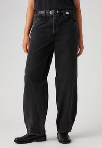 Svarta högmidjade jeans med avslappnad passform, med rak benmodell, blekt tvätt och ett svart bälte med silverspänne.