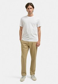 Hvid kortærmet t-shirt, khaki lige pasform bukser, lyse sneakers. Glatte teksturer, afslappet design, minimalistisk stil.