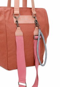 Sac fourre-tout en tissu terre cuite avec des sangles synthétiques roses, une quincaillerie argentée et une poignée tressée grise décorative. Comprend une étiquette à l'avant.