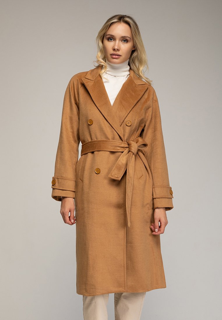 Cappotto beige doppiopetto realizzato in tessuto morbido, con cintura in vita, grandi bottoni e un ampio colletto. Maniche lunghe con dettagli a bottone.