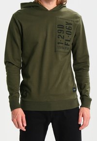 Oliivinvihreä huppari, jossa on etutasku painetuin yksityiskohdin, pitkät hihat sekä resorit hihansuissa ja helmassa lisättyä tekstuuria varten.