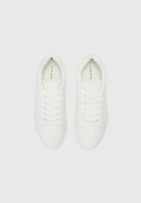 White sneakers with a smooth synthetic upper, flat lace closure, padded collar, and rubber sole. Minimalist design with no visible patterns.