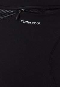 Närbild av svart tyg med dragkedja och vit "CLIMACOOL" märkning på andningsbar träningsklädsel.