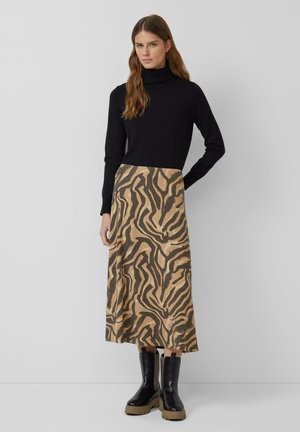 Czarny sweter z golfem, luźny krój, w połączeniu z jasnobrązową spódnicą z czarnym wzorem zwierzęcym. Czarne botki za kostkę z masywną podeszwą.