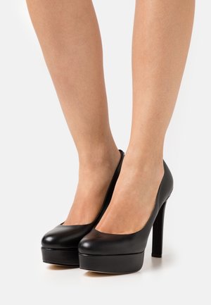 Scarpe con tacco alto nere con una texture liscia in pelle, punta a mandorla e suola platform, caratterizzate da un tacco a spillo sottile.