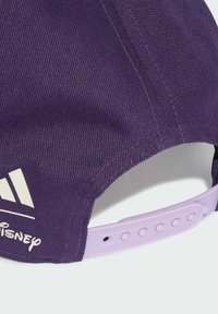 Gorra morada con una tela texturizada, que presenta un logo blanco de Adidas y texto de Disney. La correa ajustable es de color morado claro y tiene agujeros para el ajuste.