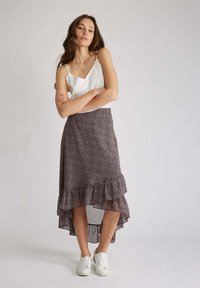 Jupe fluide asymétrique à motif floral sombre avec des détails volantés. Associée à un top en dentelle blanc et des baskets blanches. Tissu lisse et léger.